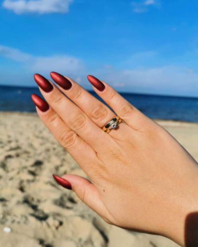 najlepszy manicure Gliwice, piękne przedłużane paznokcie o bordowym, matowym kolorze na tle morza